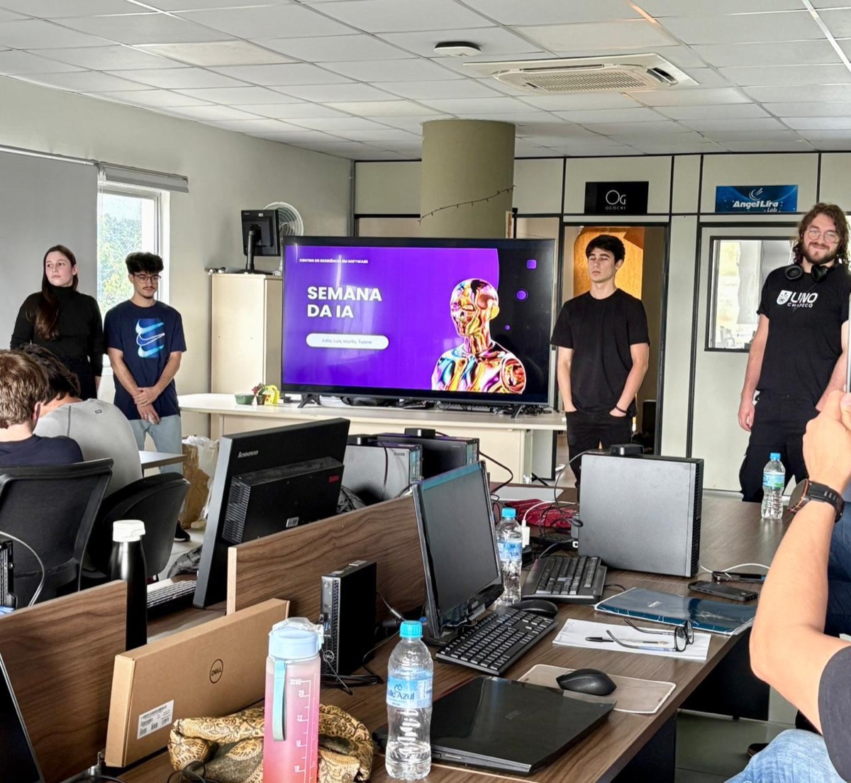 Grupo de residentes apresentando o slide de abertura "Semana da IA".