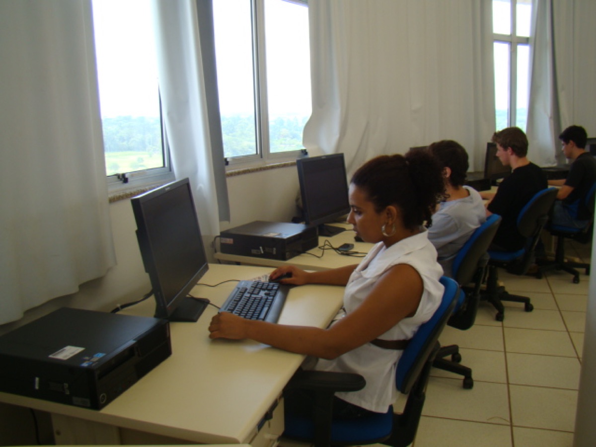 Residente programando em uma estação de trabalho do laboratório, ao lado de colegas.