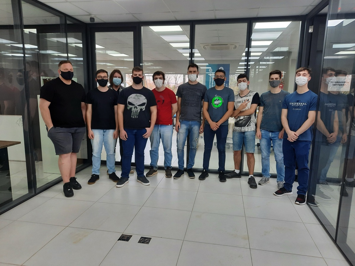 Turma de residentes de 2021 de máscara, reunida em sala envidraçada.