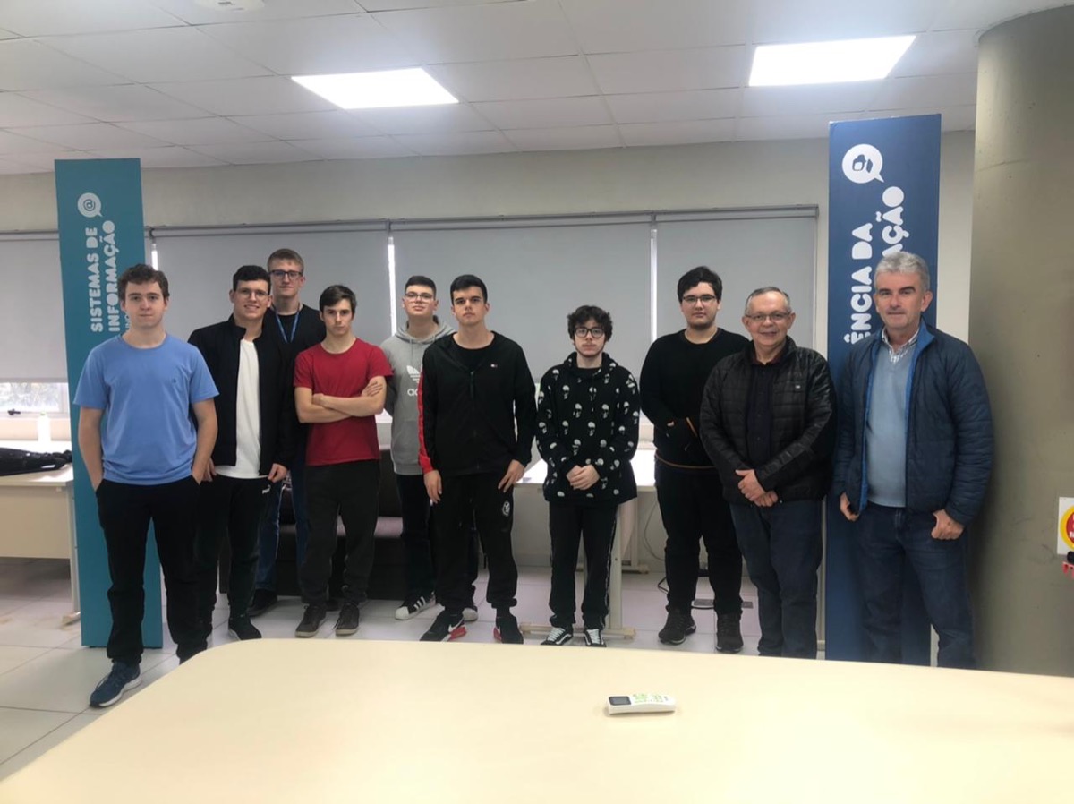Turma de residentes de 2022 entre banners dos cursos de Sistemas de Informação e Ciência da Computação.